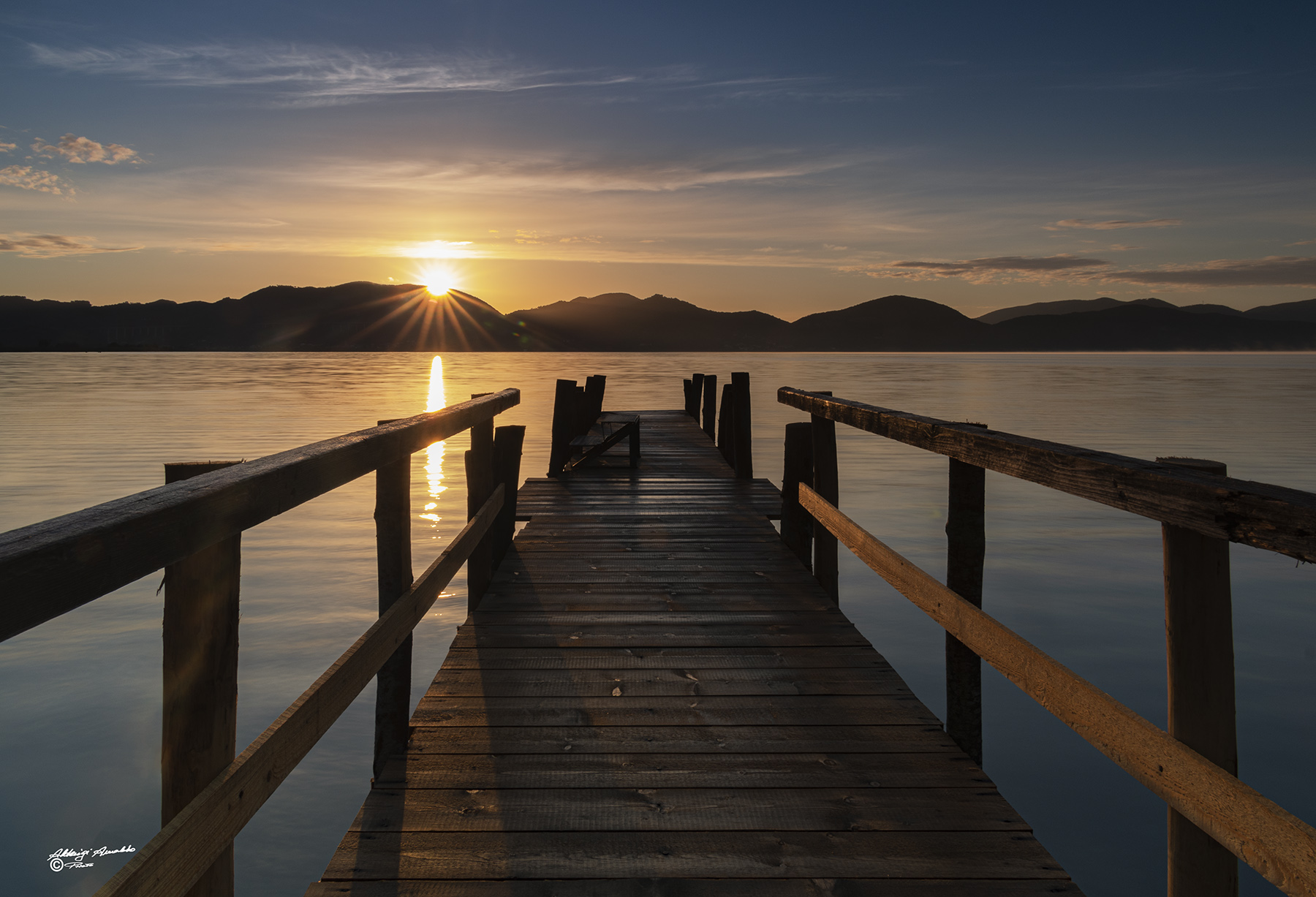IL pontile al sorgere del sole. Lago Puccini.