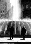 due silhouette di persone fissano l'imprendibile getto della fontana, che fa scorrere il tempo e pensieri