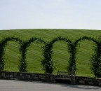 piazzetta circolare con archi e collina con prato rasato