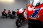 Sullo sfondo della moto di Stoner si riconosce Filippo Preziosi, Direttore Generale di Ducati Corse che rilascia un'intervista