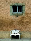 Una finestra con grate, una poltroncina bianca. (Linee caden Una finestra con grate, una poltroncina bianca. (Linee caden