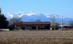 Prime luci in una giornata invernale a Fossano, dietro l'azienda le punte dei monti sono innevate.