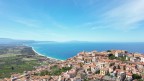 "Panorama mozzafiato del maestoso Monte Etna che sovrasta il Mar Tirreno, con il suggestivo borgo costiero di Nicotera Marina in primo piano."